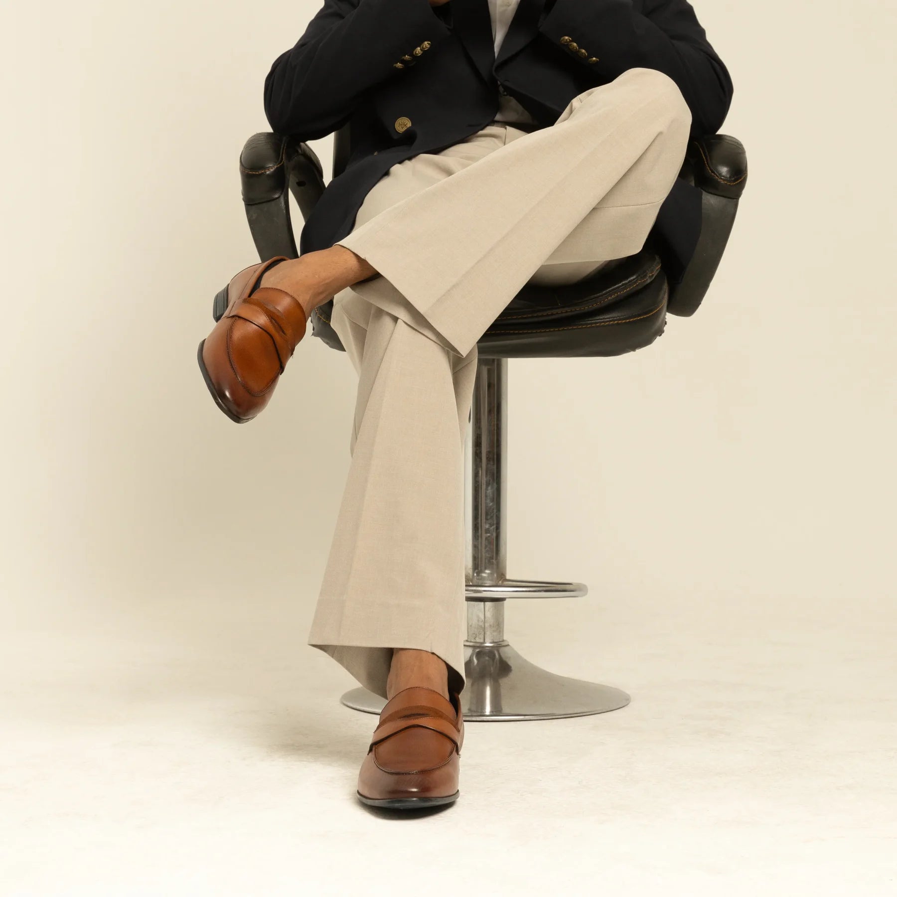 Man seated in a tailored outfit wearing brown leather loafers