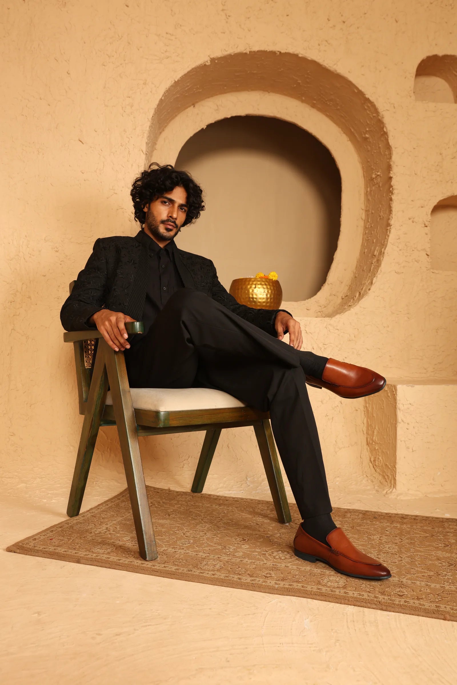 Man seated in a tailored outfit wearing brown leather loafers